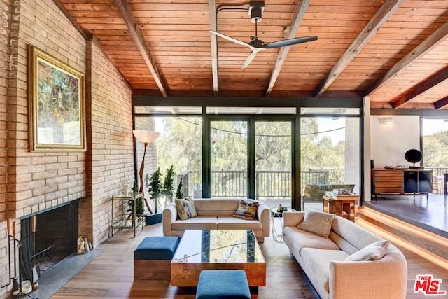 sunroom / solarium with lofted ceiling with beams, ceiling fan, wooden ceiling, and a brick fireplace