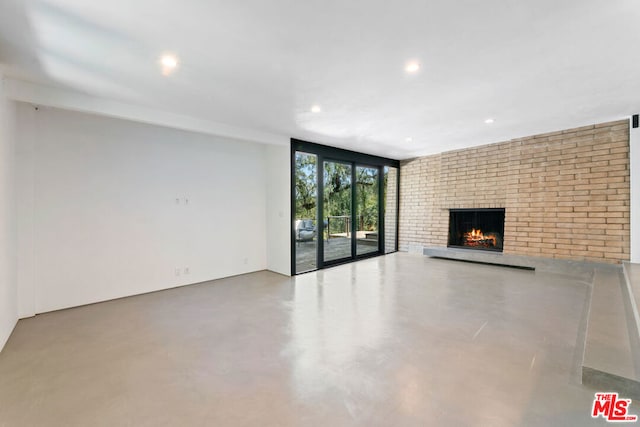 unfurnished living room with a fireplace and concrete floors