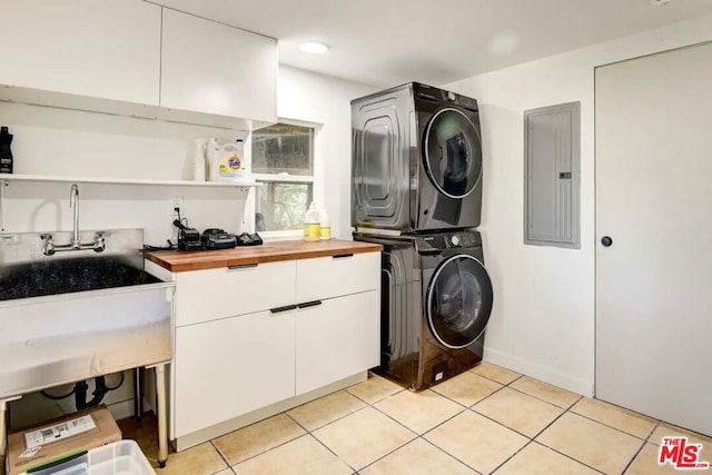 laundry room with cabinets, light tile patterned floors, electric panel, and stacked washing maching and dryer