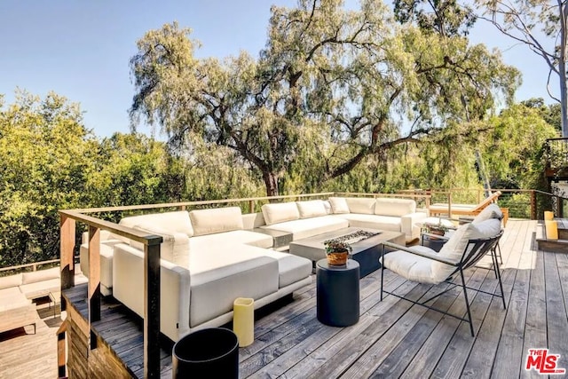 wooden deck featuring an outdoor living space with a fire pit