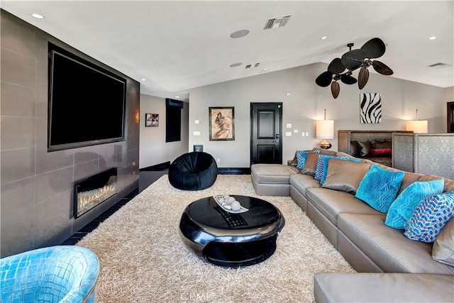 living room featuring ceiling fan, a large fireplace, and vaulted ceiling