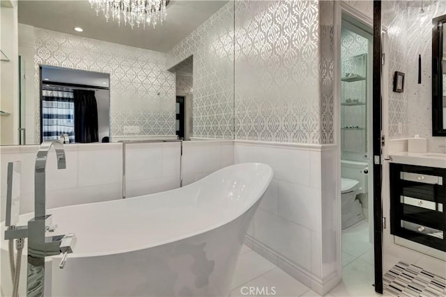 bathroom featuring tile patterned flooring, a chandelier, toilet, a bathtub, and vanity