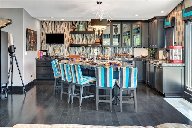 kitchen featuring pendant lighting, sink, gray cabinetry, and dark stone countertops