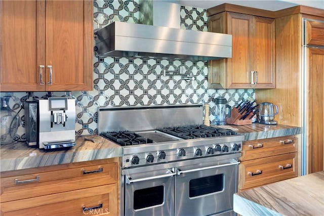 kitchen featuring wood counters, tasteful backsplash, wall chimney exhaust hood, hardwood / wood-style flooring, and range with two ovens