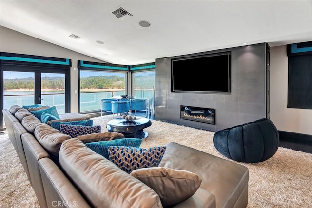 living room with lofted ceiling, a tile fireplace, and french doors