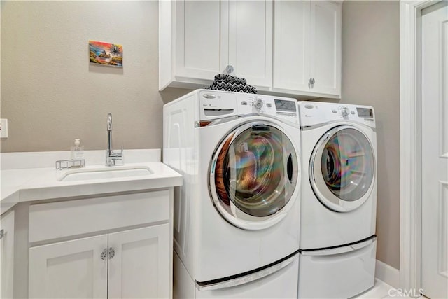 clothes washing area featuring cabinets, washing machine and dryer, and sink