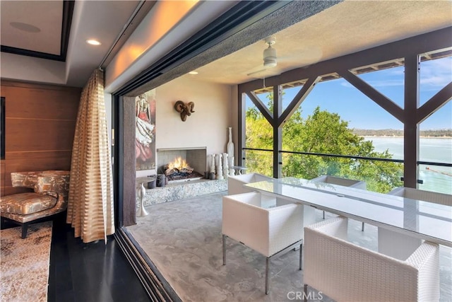 sunroom featuring ceiling fan and a water view