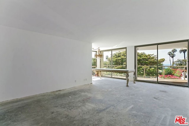 spare room with concrete flooring and a chandelier