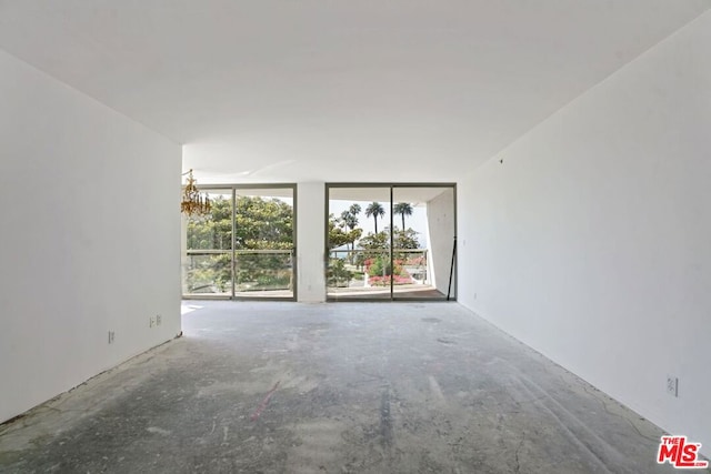 empty room featuring a notable chandelier and concrete flooring