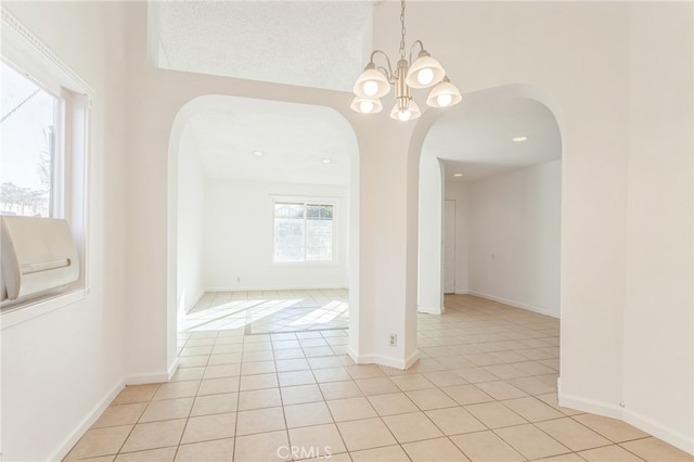 unfurnished dining area featuring a notable chandelier, a textured ceiling, and light tile patterned floors