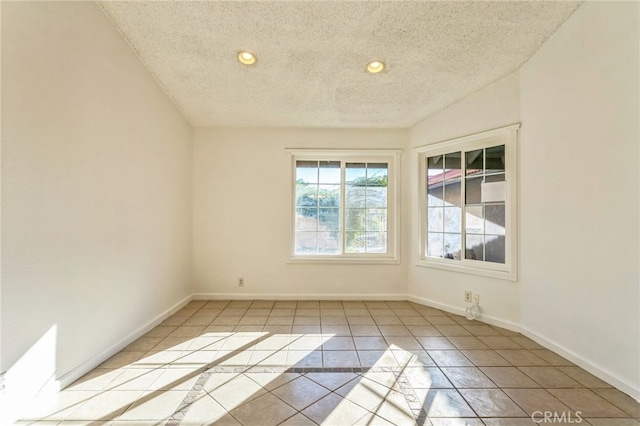 tiled spare room with a textured ceiling and lofted ceiling