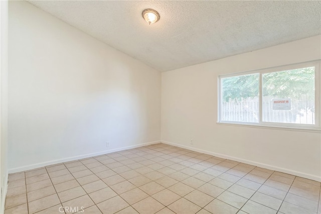 tiled empty room with lofted ceiling and a textured ceiling