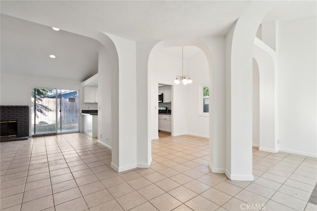 unfurnished living room featuring a notable chandelier, a textured ceiling, and light tile patterned floors