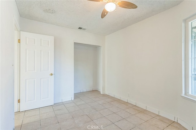 unfurnished bedroom with a closet, ceiling fan, a textured ceiling, and light tile patterned flooring