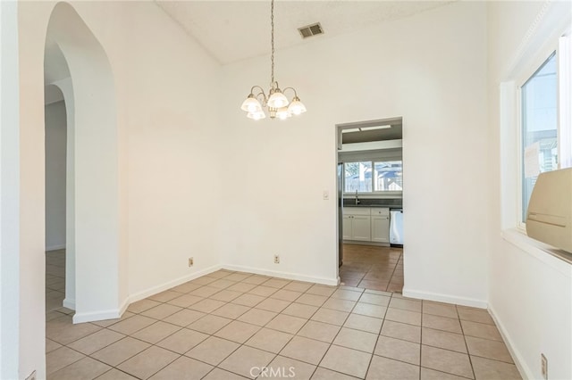 empty room with sink, high vaulted ceiling, a notable chandelier, and light tile patterned floors