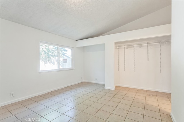 interior space featuring a textured ceiling, lofted ceiling, and light tile patterned floors