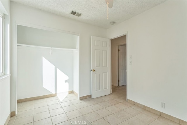 tiled empty room featuring a textured ceiling and ceiling fan