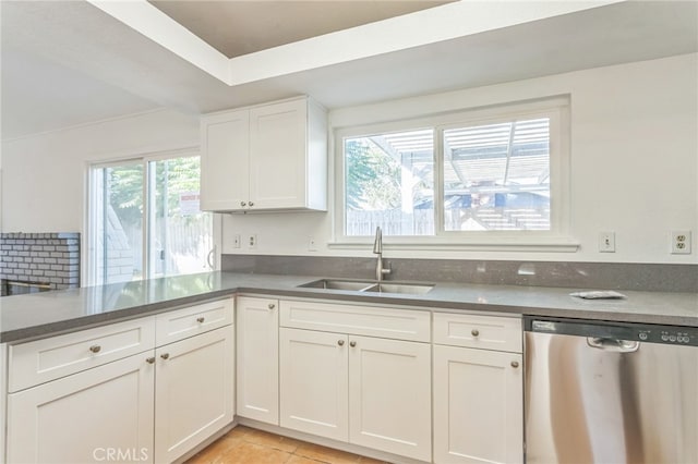 kitchen featuring kitchen peninsula, light tile patterned floors, white cabinetry, stainless steel dishwasher, and sink