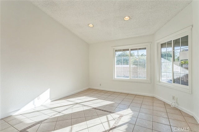 unfurnished room featuring lofted ceiling, light tile patterned flooring, and a textured ceiling