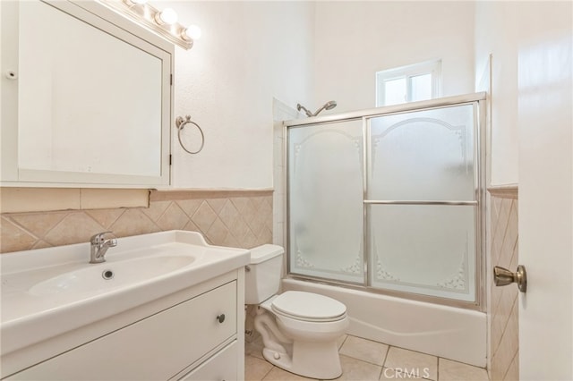 full bathroom featuring tile walls, shower / bath combination with glass door, toilet, vanity, and tile patterned floors