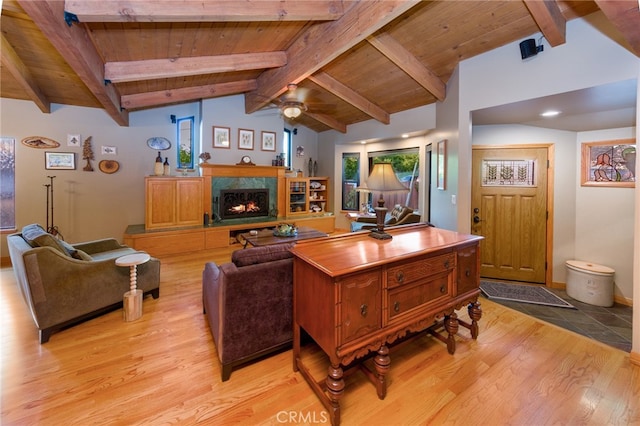 living room with vaulted ceiling with beams, light wood-type flooring, a fireplace, and wooden ceiling