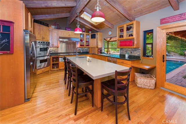 kitchen featuring vaulted ceiling with beams, sink, decorative light fixtures, light hardwood / wood-style flooring, and stainless steel appliances