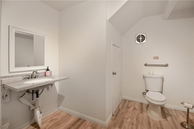 bathroom with hardwood / wood-style floors, toilet, lofted ceiling, and sink