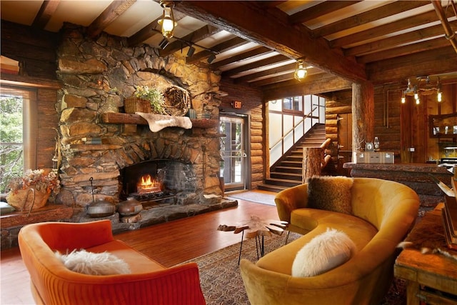 living room featuring beam ceiling, a stone fireplace, and hardwood / wood-style flooring