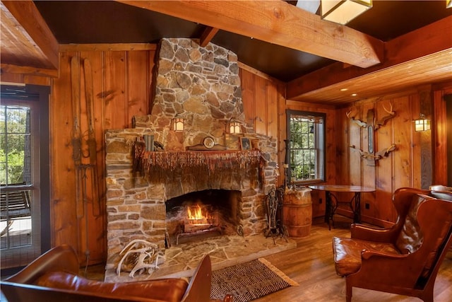 sitting room with a fireplace, light wood-type flooring, lofted ceiling with beams, and wooden walls