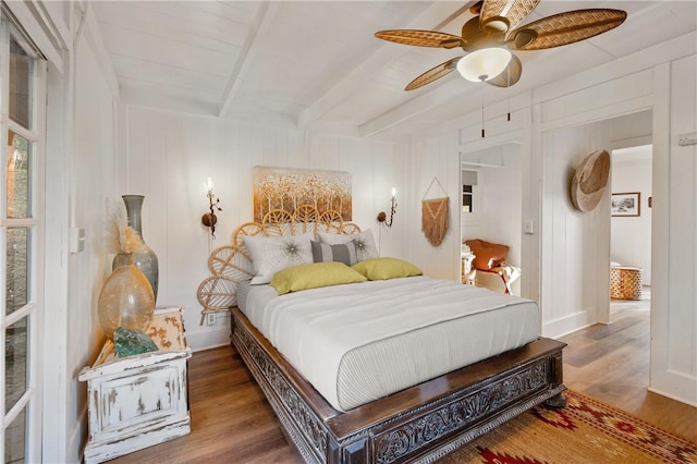 bedroom with ceiling fan, beam ceiling, and wood-type flooring