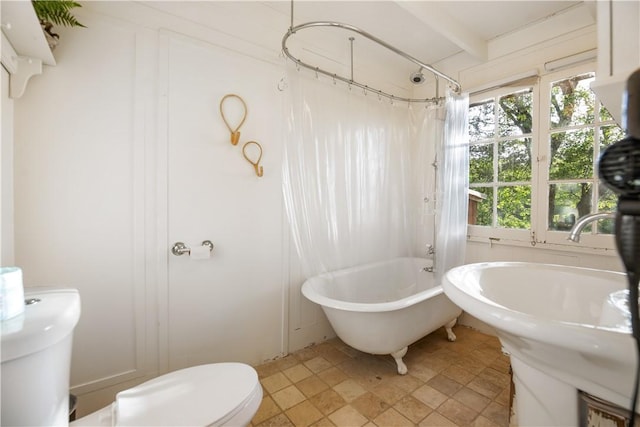 bathroom featuring shower / bath combo, toilet, and a wealth of natural light