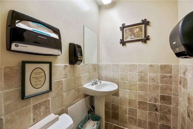 bathroom featuring tile walls and toilet