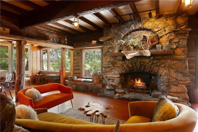 sunroom featuring beamed ceiling and a stone fireplace