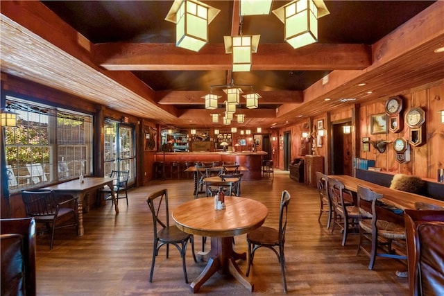 dining room with wooden walls, hardwood / wood-style floors, and beamed ceiling