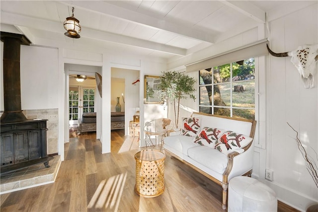 sunroom featuring a wood stove, ceiling fan, and beamed ceiling