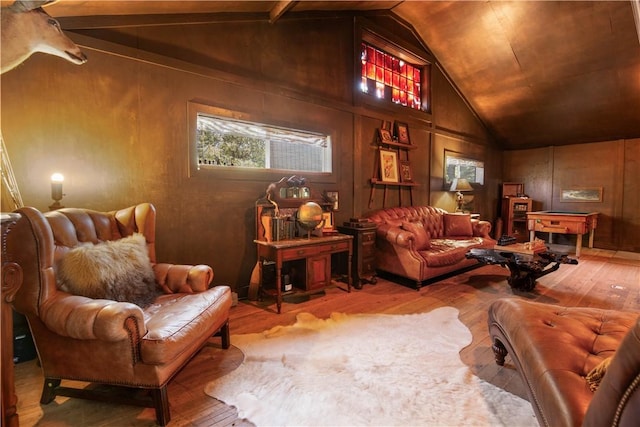 sitting room with hardwood / wood-style floors, vaulted ceiling with beams, and wood walls