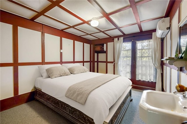 carpeted bedroom with a wall unit AC and coffered ceiling