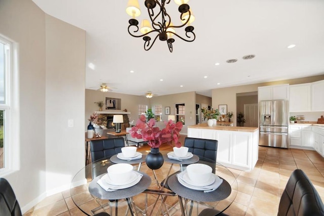 tiled dining area with ceiling fan with notable chandelier