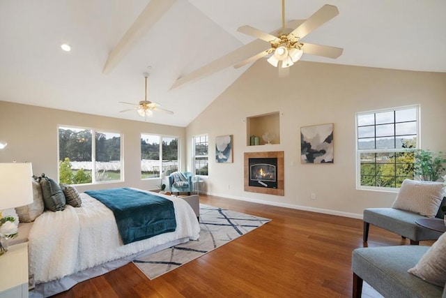 bedroom featuring ceiling fan, a tile fireplace, beamed ceiling, hardwood / wood-style flooring, and high vaulted ceiling