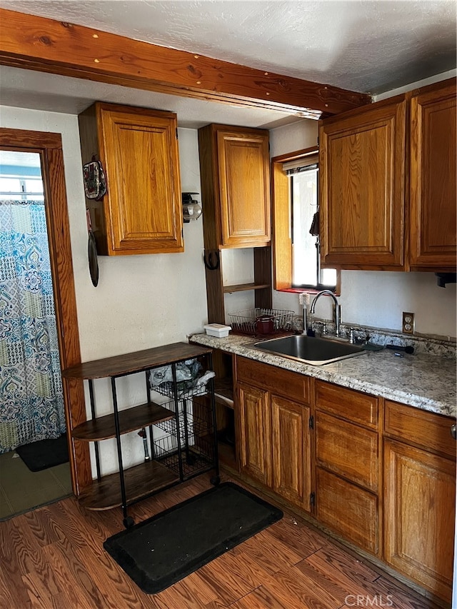 kitchen featuring sink, light stone countertops, and dark wood-type flooring