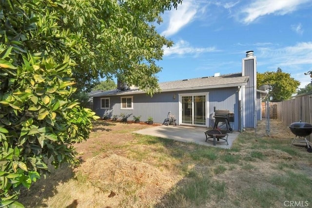 back of property featuring a yard, a patio area, and a fire pit