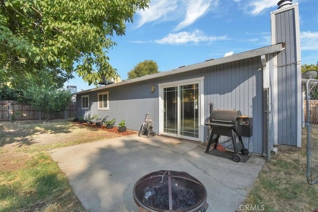 rear view of property featuring a patio and a fire pit