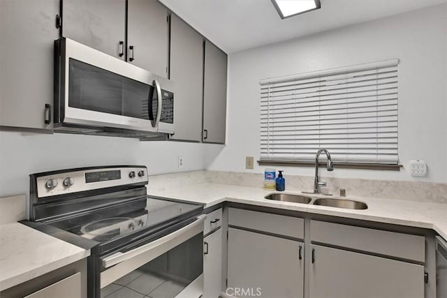 kitchen featuring sink, tile patterned floors, appliances with stainless steel finishes, and gray cabinetry