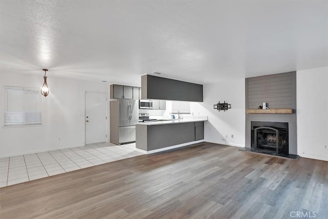 unfurnished living room with light hardwood / wood-style floors, a textured ceiling, and a large fireplace