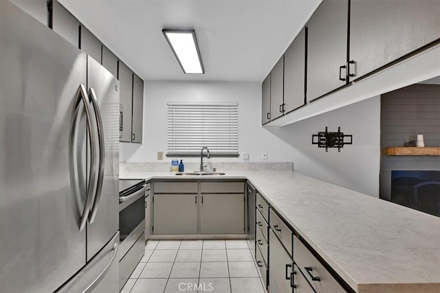 kitchen with light tile patterned floors, kitchen peninsula, sink, and stainless steel appliances