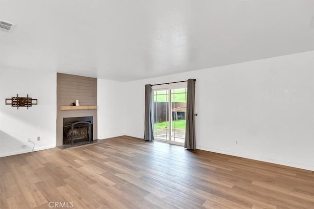 unfurnished living room with a large fireplace and light hardwood / wood-style flooring