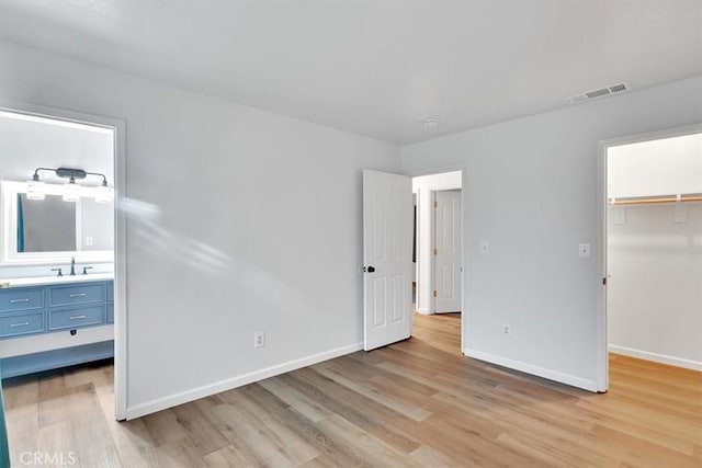 unfurnished bedroom with a spacious closet, a closet, light hardwood / wood-style flooring, and sink