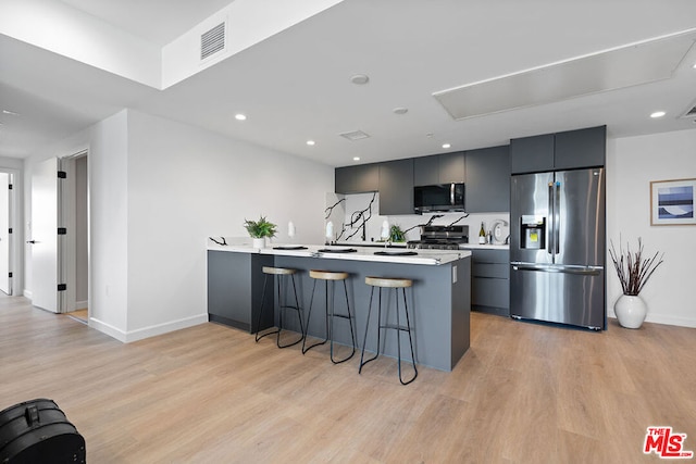 kitchen featuring light hardwood / wood-style flooring, stainless steel appliances, kitchen peninsula, and a breakfast bar area