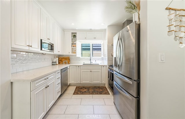 kitchen featuring light tile patterned flooring, sink, white cabinetry, backsplash, and appliances with stainless steel finishes