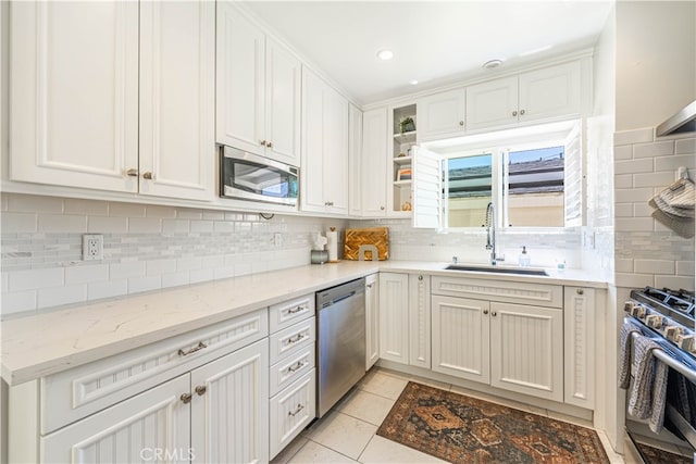 kitchen with light tile patterned floors, white cabinets, appliances with stainless steel finishes, and sink